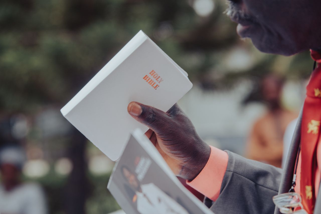 Adult man holding a Holy Bible, participating in an outdoor event, Ibadan, Nigeria.