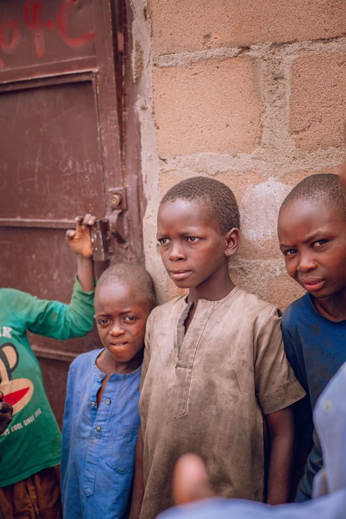 Group of children posing near a building in Gombe, Nigeria. Warm tones and candid expressions.