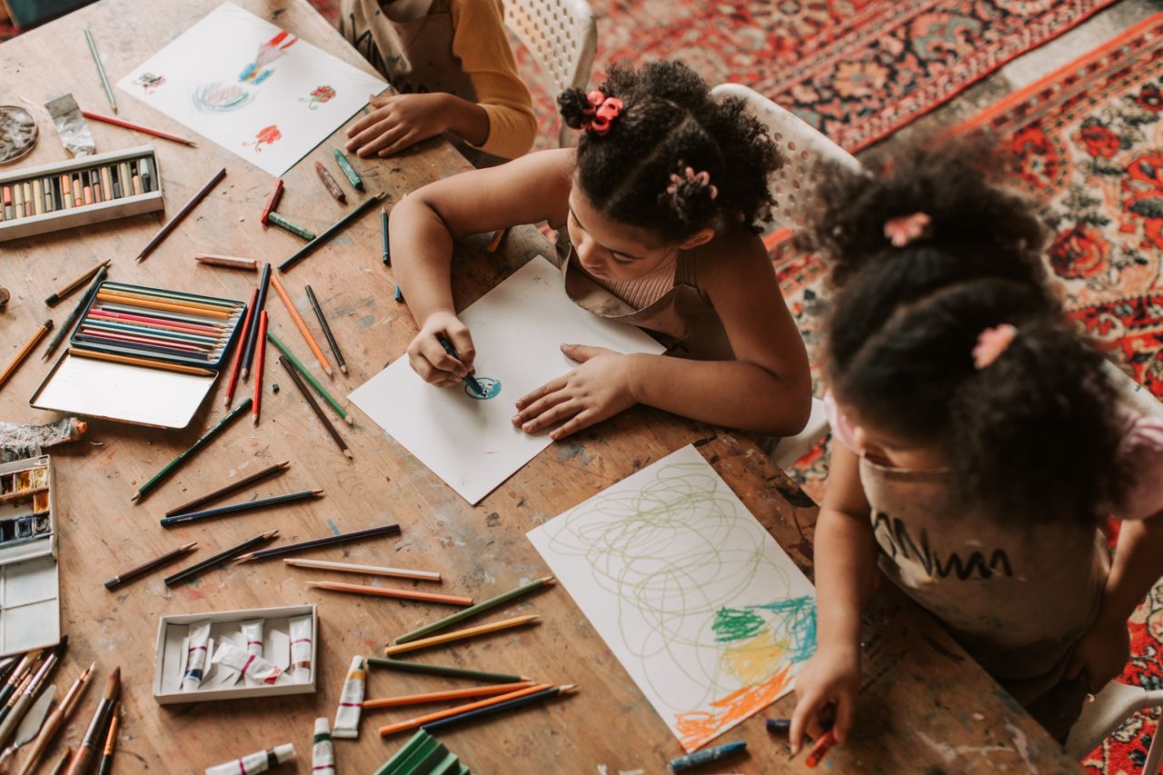 Home Children drawing with colored pencils and papers indoors, showcasing creativity.