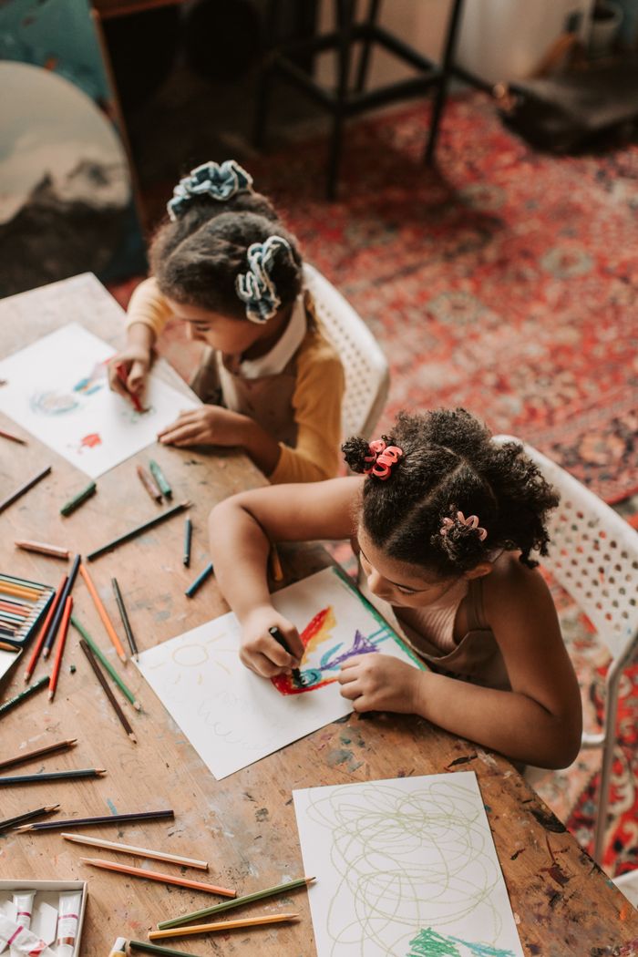 Home Two kids coloring and drawing with pencils in an artistic setting.